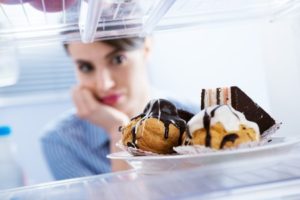 25919357-young-hungry-woman-in-front-of-refrigerator-craving-chocolate-pastries